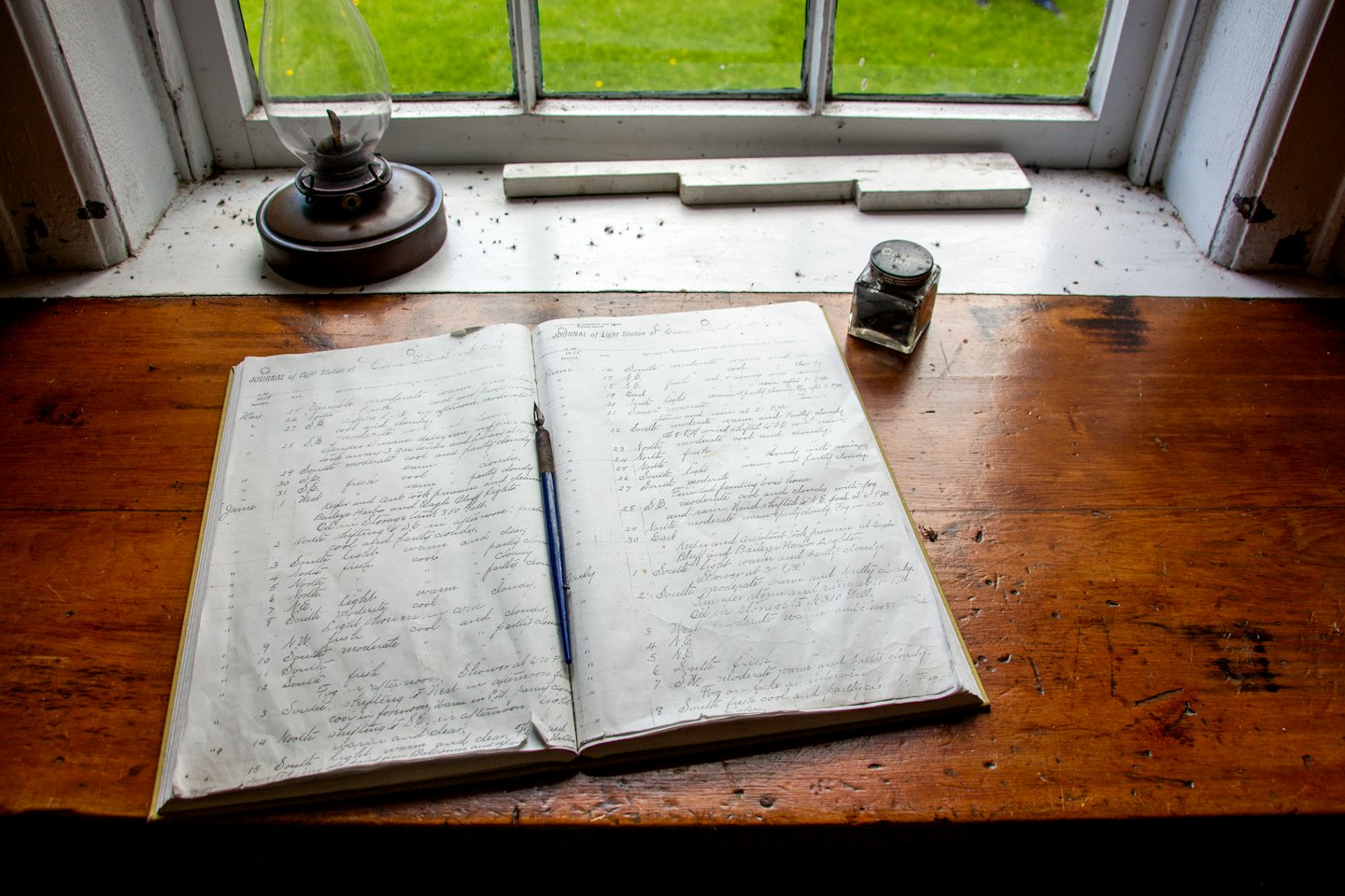 An open ledger with a dip pen on a wooden desk.